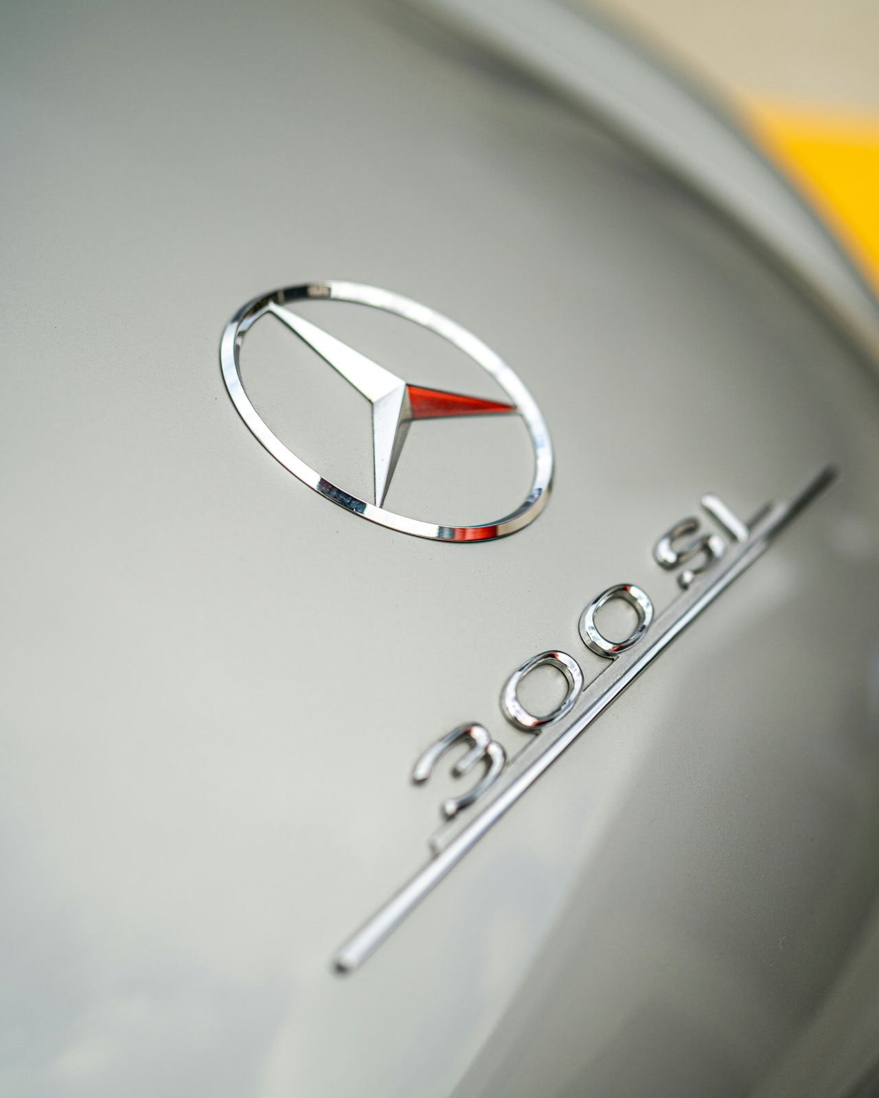 Mercedes-Benz emblem and 300 SL badge on a silver vehicle, photographed in 2021
